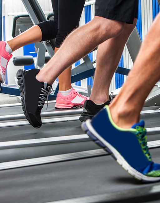 Group of legs wearing sneakers running on treadmill at sport gym.